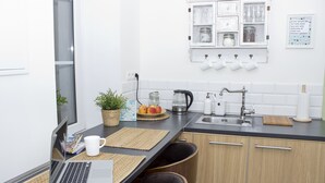 Una cocina moderna con una computadora portátil sobre la encimera, una cafetera y un lavamanos.
