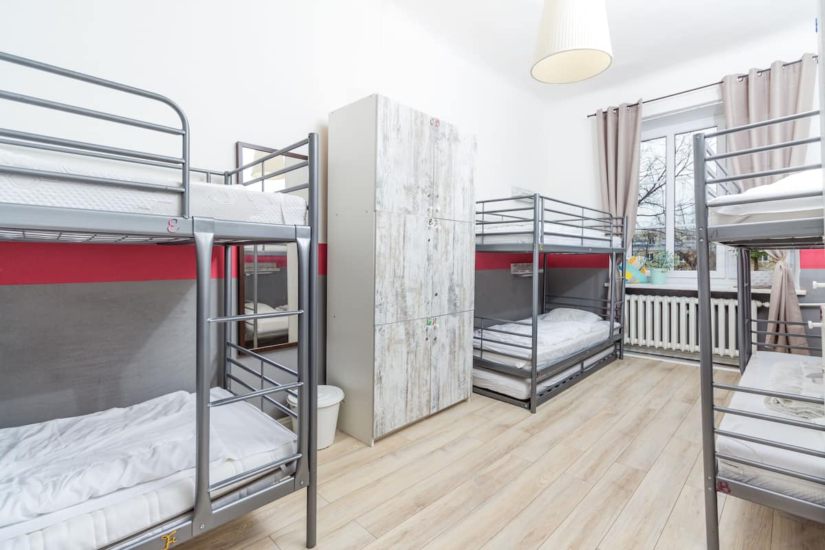 Une chambre de dortoir avec des lits superposés, une armoire et une fenêtre avec des rideaux.