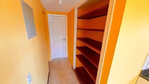 A narrow hallway with a white door at the end, leading to a room with a red carpet and a white ceiling light. - Bon Bini Pousada (Búzios)