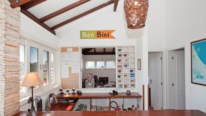A cozy interior with a wooden counter, a stone wall, and a sign reading "Bon Bini". - Bon Bini Pousada (Búzios)