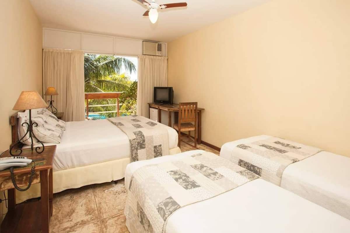 Habitació d'hotel amb dos llits, escriptori amb televisió, telèfon i finestra amb cortines.