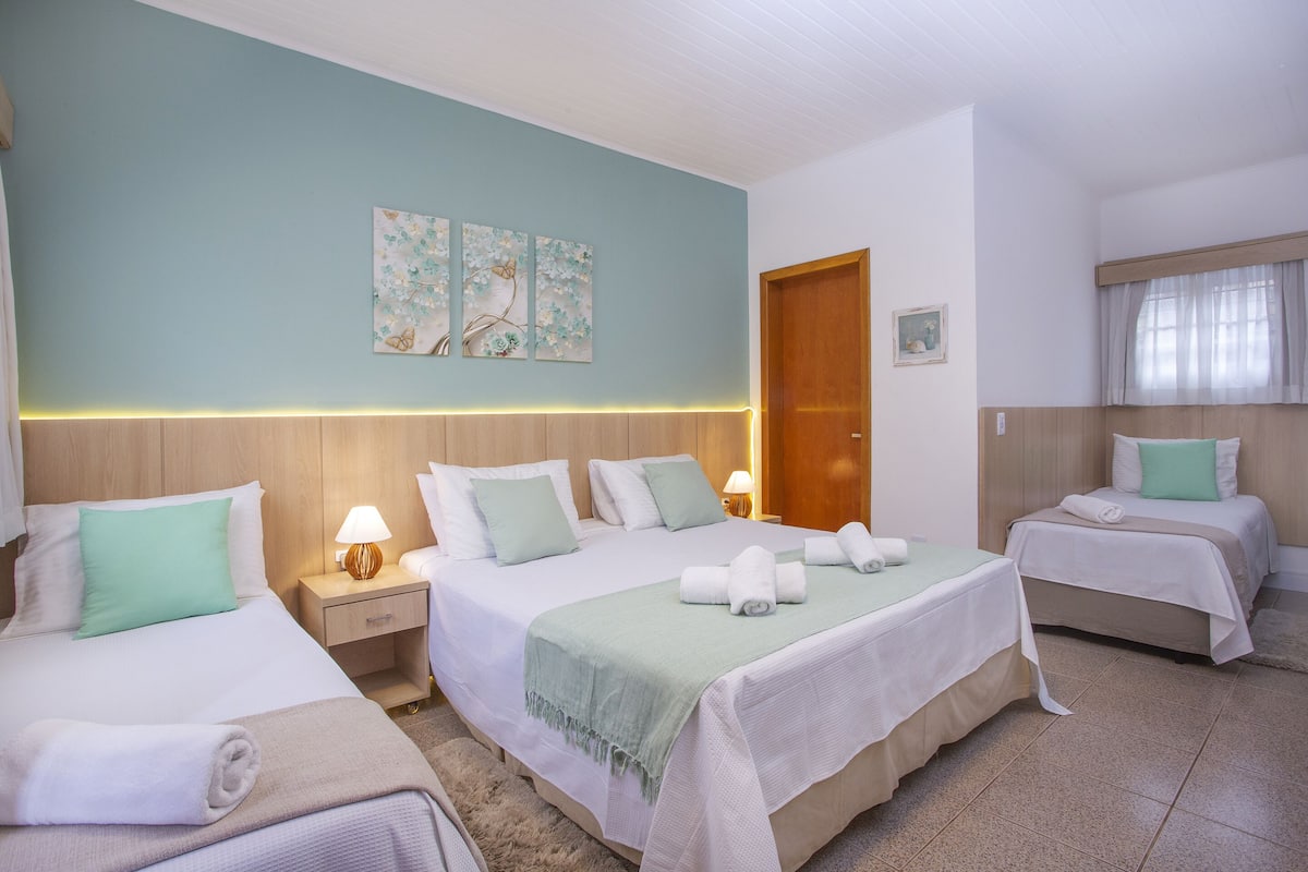 Una habitación de hotel con dos camas, un cabecero de madera, una mesita de noche con una lámpara y una puerta.