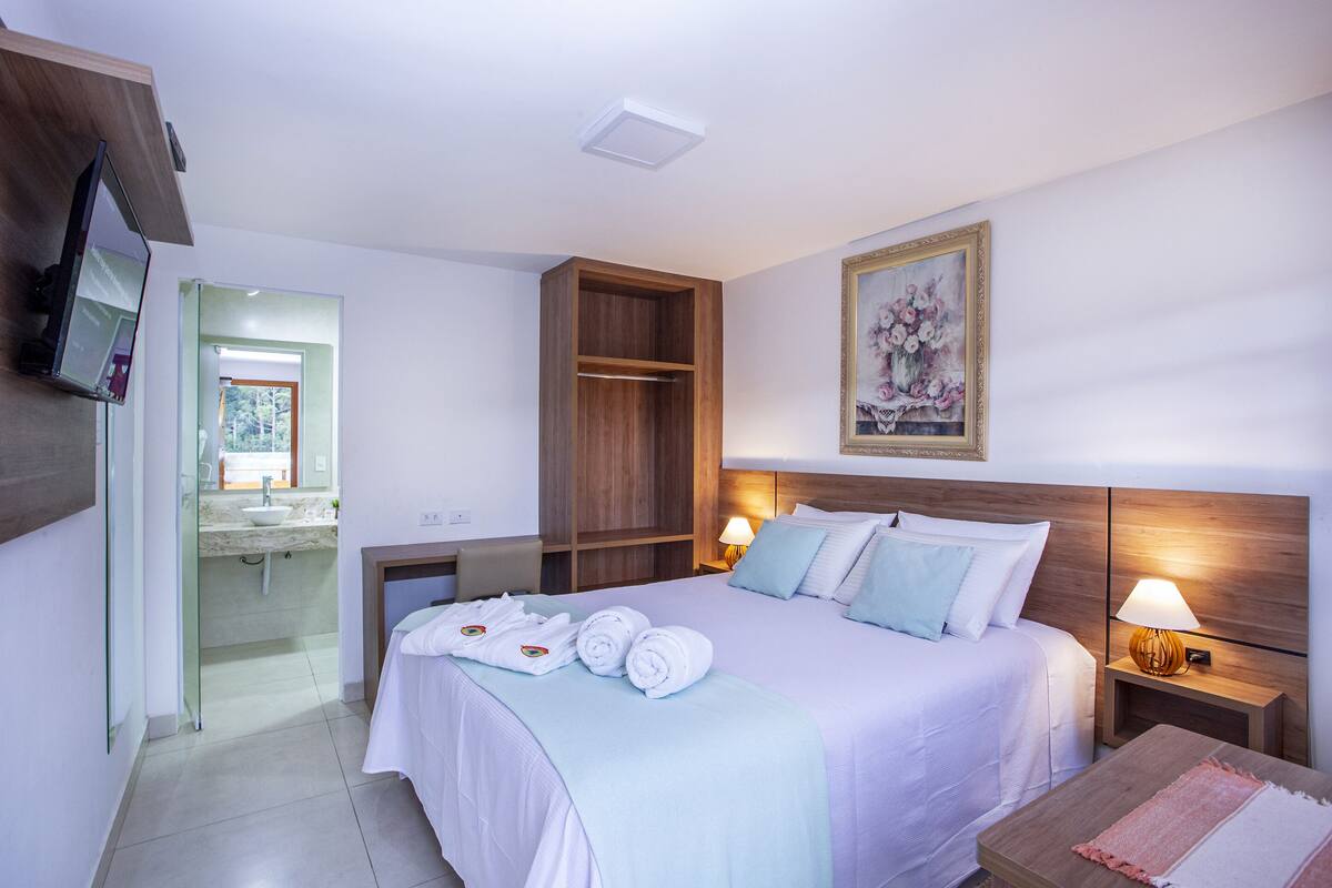 Una habitación de hotel con cama, mesita de noche y un cuadro en la pared.