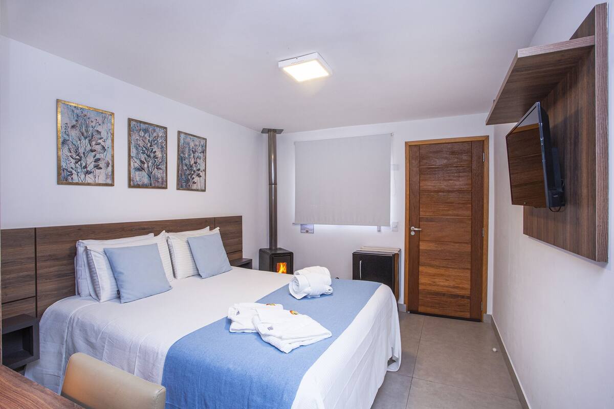 Habitación de hotel con una cama grande, cabecera de madera, un televisor de pantalla plana montado en la pared y una puerta de madera.