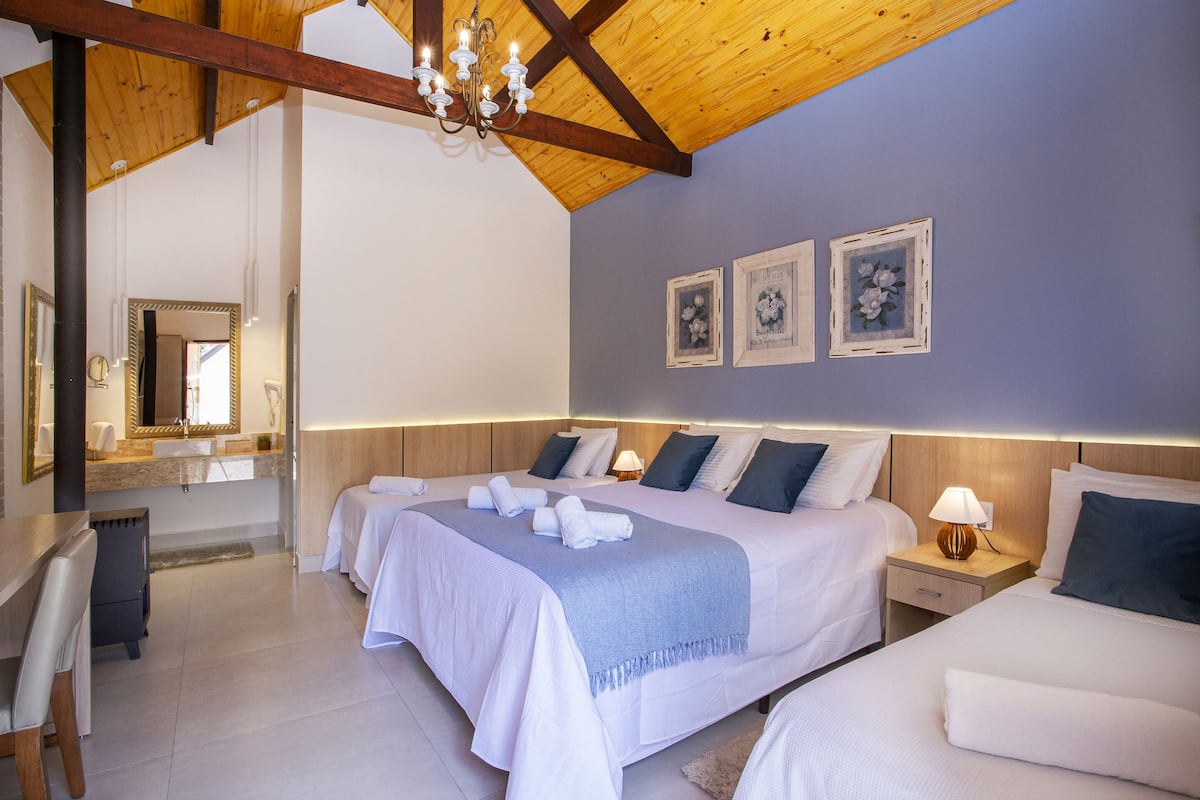 Una habitación de hotel con una cama grande, mesitas de noche, un espejo y una araña.