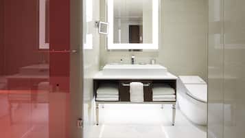 Een moderne badkamer met een douchecabine van glas, een witte wastafel en een toilet.