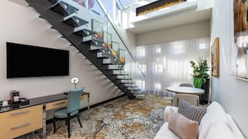 Una sala de estar moderna con una escalera, un televisor de pantalla plana, un escritorio y un sofá.