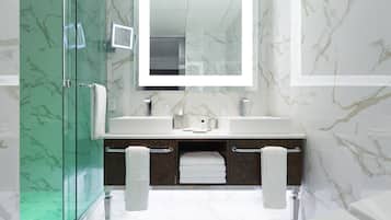 Un baño moderno con cabina de ducha de vidrio, pared con azulejos de mármol, espejo grande y tocador doble.