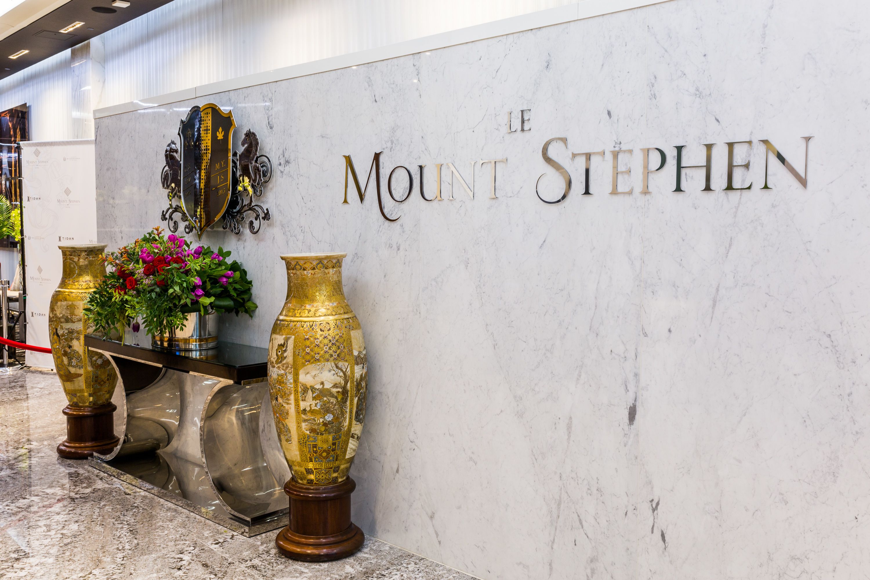 Ein marmorner Empfangstresen mit der Aufschrift "LE MOUNT STEPHEN" und zwei aufwendigen Vasen.