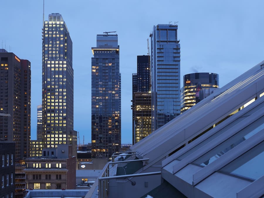 A cityscape with high-rise buildings, including a prominent skyscraper with a crane on top, suggesting ongoing construction.