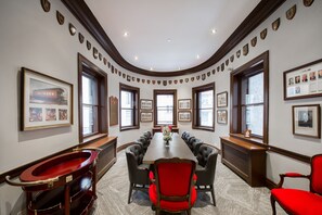 A conference room with a long table, leather chairs, and framed pictures on the walls.