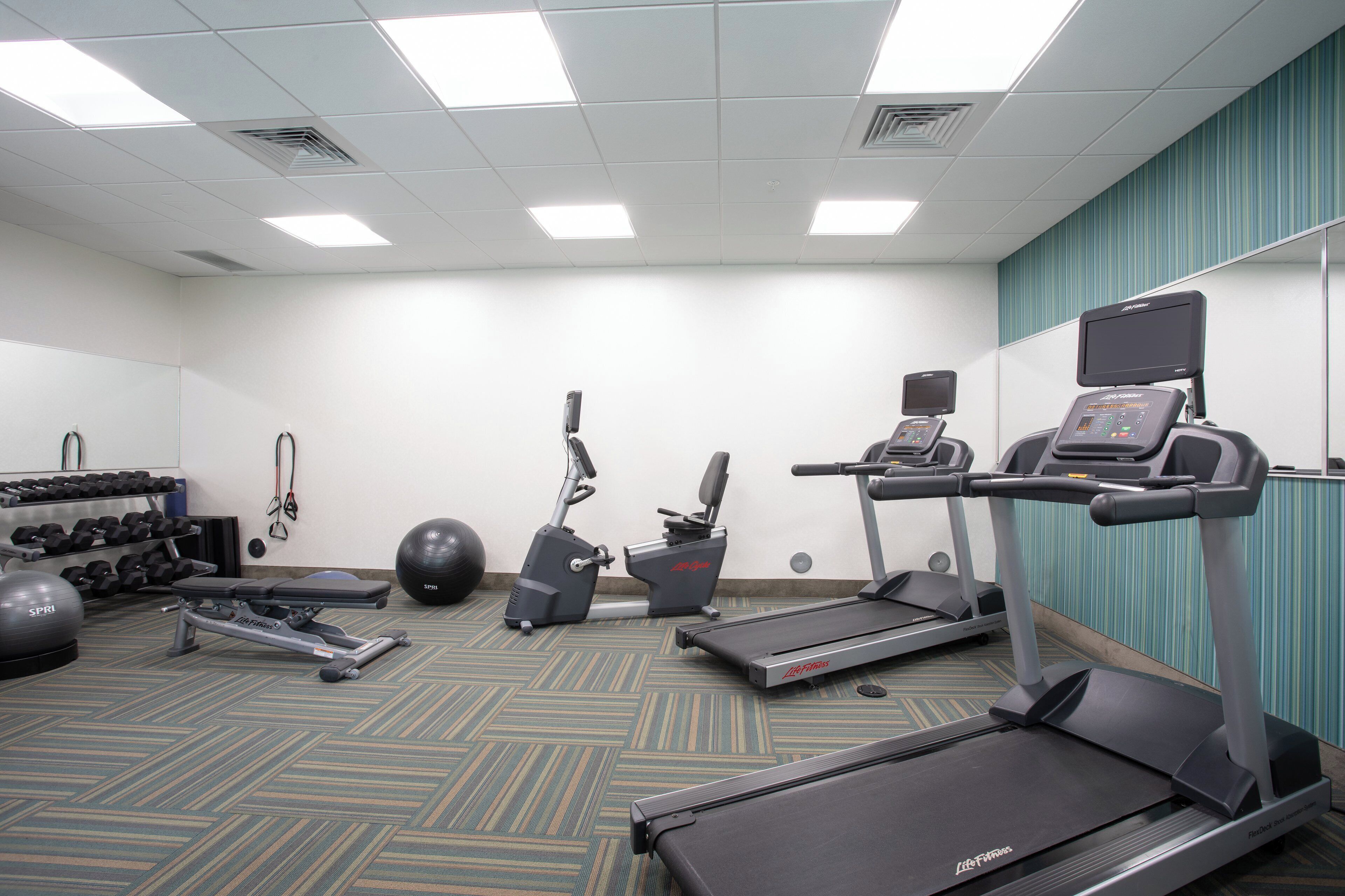 Gimnasio con cintas de correr, elíptica, mancuernas y pelotas de ejercicio.