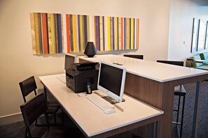Ein moderner Arbeitsplatz mit Schreibtisch, Computer, Drucker und Stühlen.