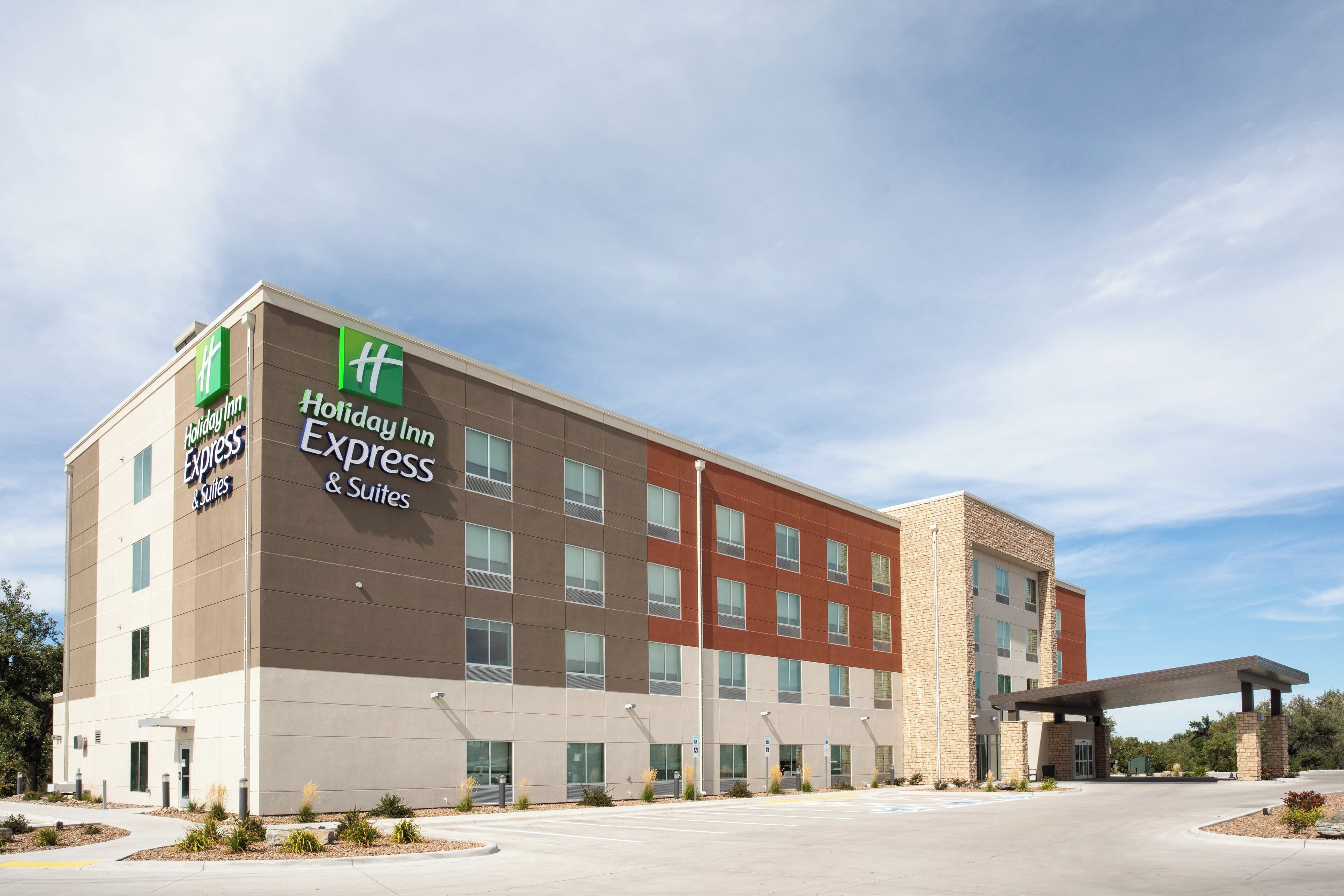 Un hôtel Holiday Inn Express & Suites au design moderne, doté d’un toit plat et d’une façade combinant des éléments en brique et en stuc.