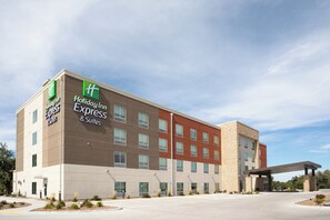Ein Hotel Holiday Inn Express & Suites mit modernem Design, das ein flaches Dach und eine Fassade aus Ziegeln und Putz aufweist.