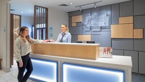 A reception desk with a modern design, a digital screen, and a sign indicating hotel services. - Holiday Inn Express & Suites Sterling by IHG (Sterling)