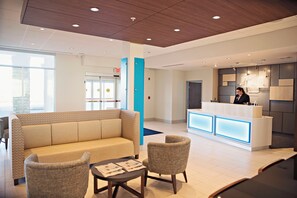 A modern reception area with a sofa, chairs, a reception desk, and a blue pillar. - Holiday Inn Express & Suites Sterling by IHG (Sterling)