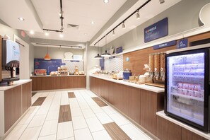 A modern breakfast area with a self-serve station, a bakery section, and a refrigerated display of dairy products. - Holiday Inn Express & Suites Sterling by IHG (Sterling)