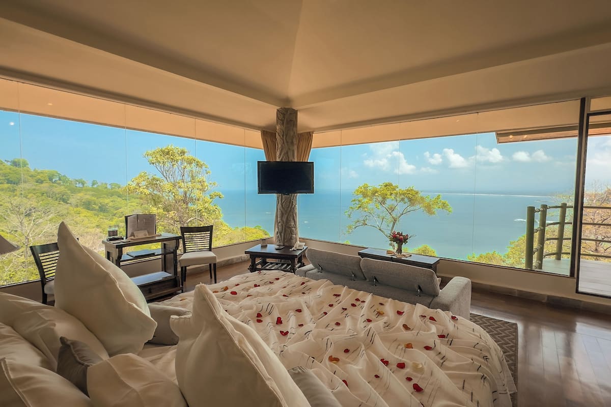 A bedroom with a large window overlooking a scenic view.