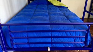 A bed with a blue mattress and a green blanket. - Hostal Possada Atacameña (San Pedro de Atacama)