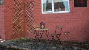 Un bâtiment en briques rouges avec une fenêtre, une table et des chaises en bois, et une lanterne.