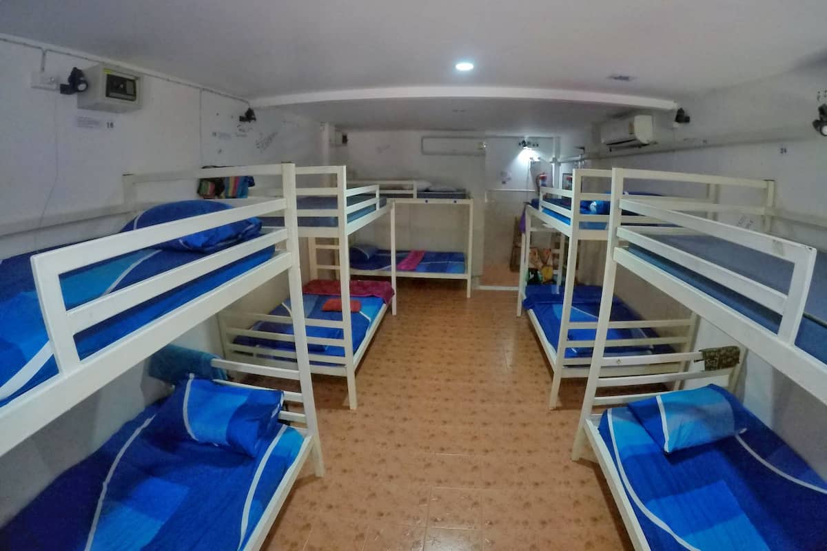 A dormitory room with bunk beds, a small table, and a wall-mounted heater.