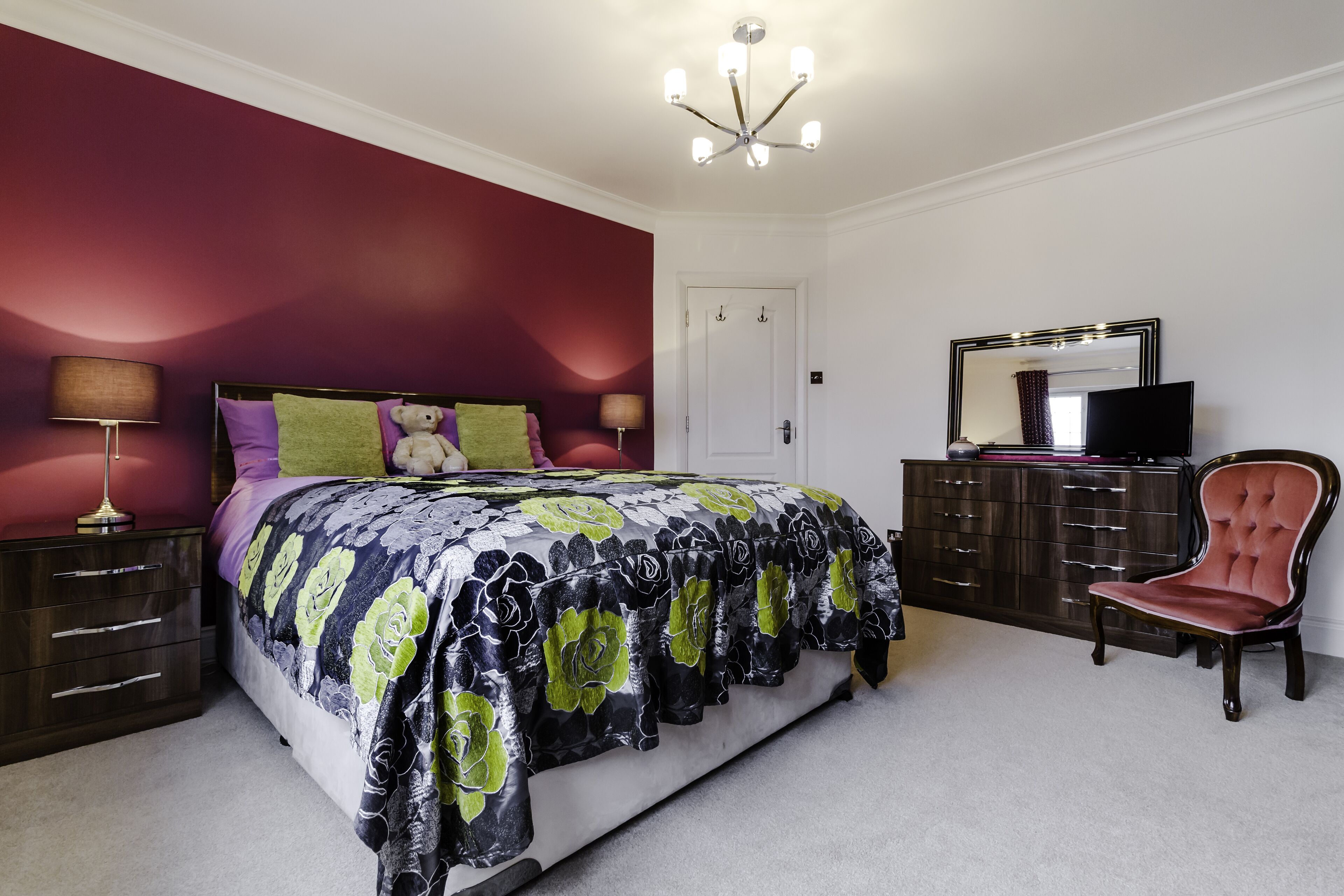 Un dormitorio con cama, cómoda, silla y televisión.