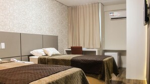 A hotel room with two beds, a desk, a chair, and an air conditioning unit. - Hotel Caju de Ouro (Feira de Santana)