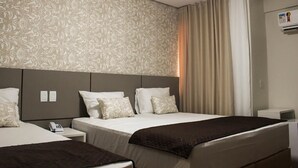 A hotel room with a large bed, a smaller bed, a bedside table with a phone, and a wall-mounted air conditioning unit. - Hotel Caju de Ouro (Feira de Santana)