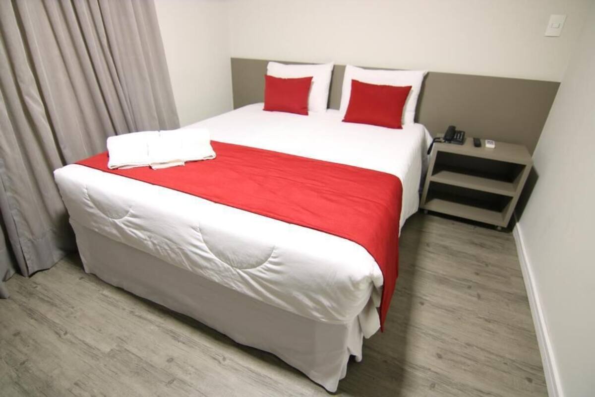 Ein Hotelzimmer mit Bett, Nachttisch und Telefon.