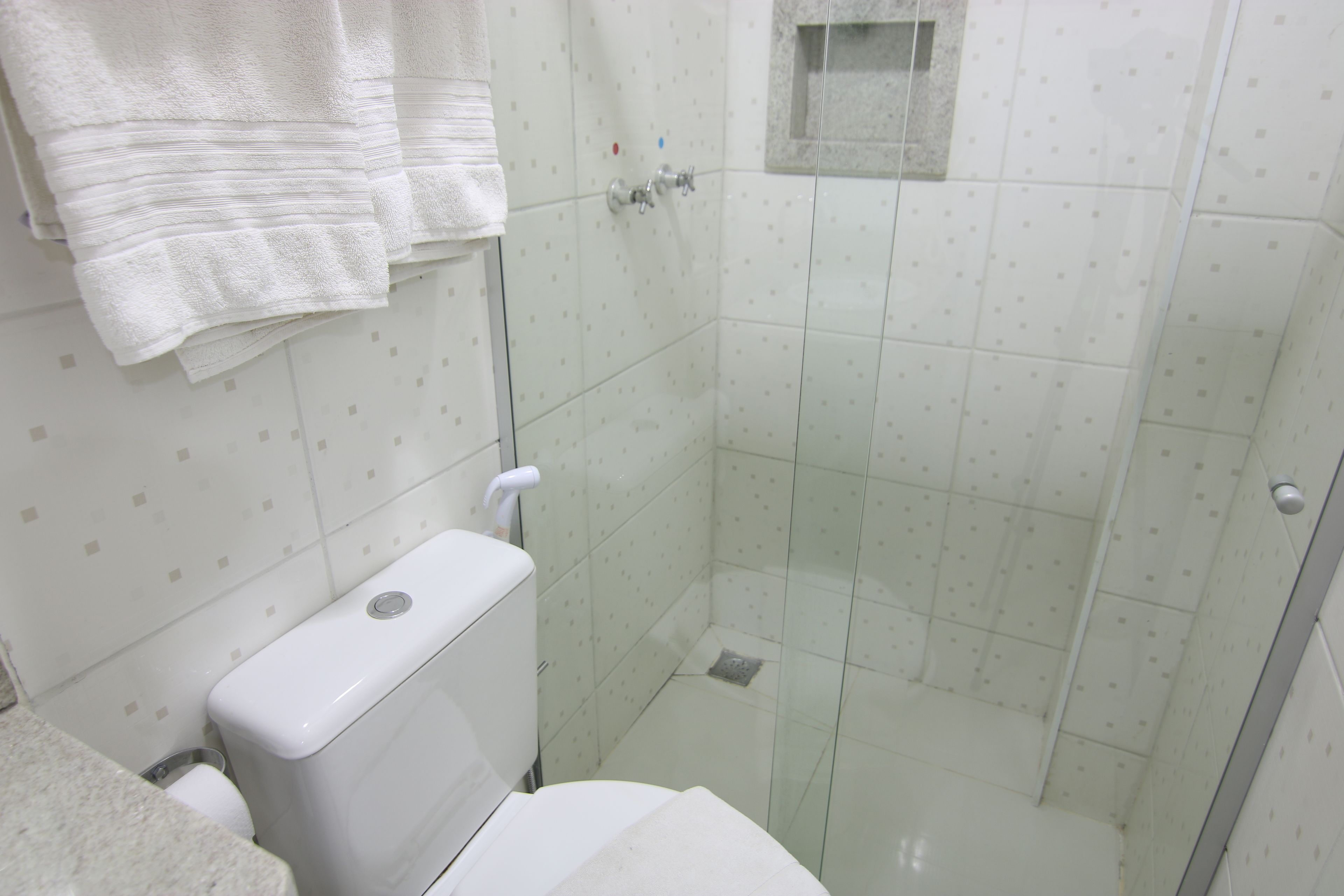 Une salle de bain avec des toilettes, une douche à parois de verre et une petite fenêtre.