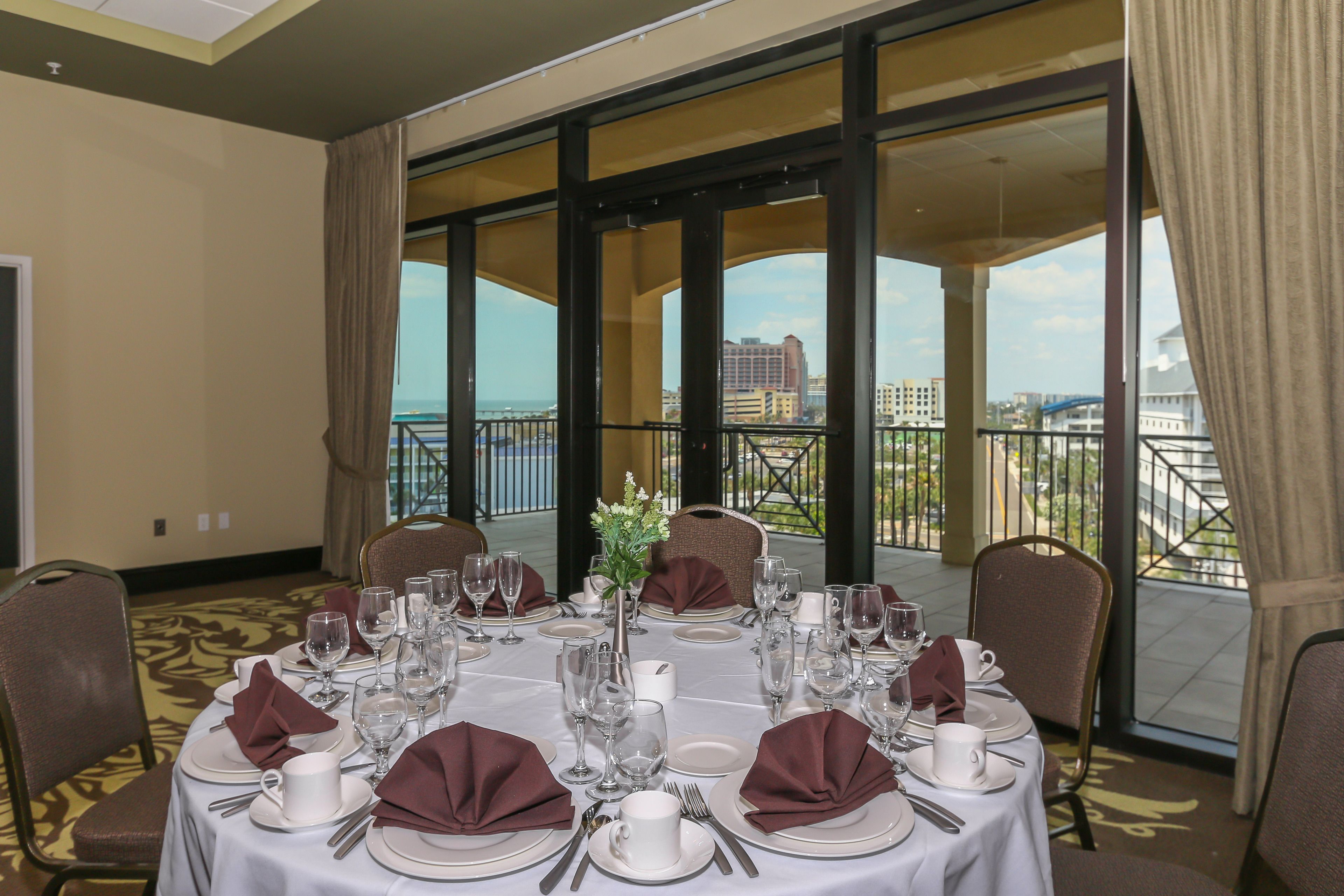 A dining table set for a meal with a view of the city and a balcony.