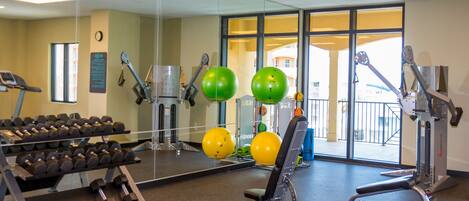 A gym with exercise equipment, a treadmill, and a mirror reflecting the room.