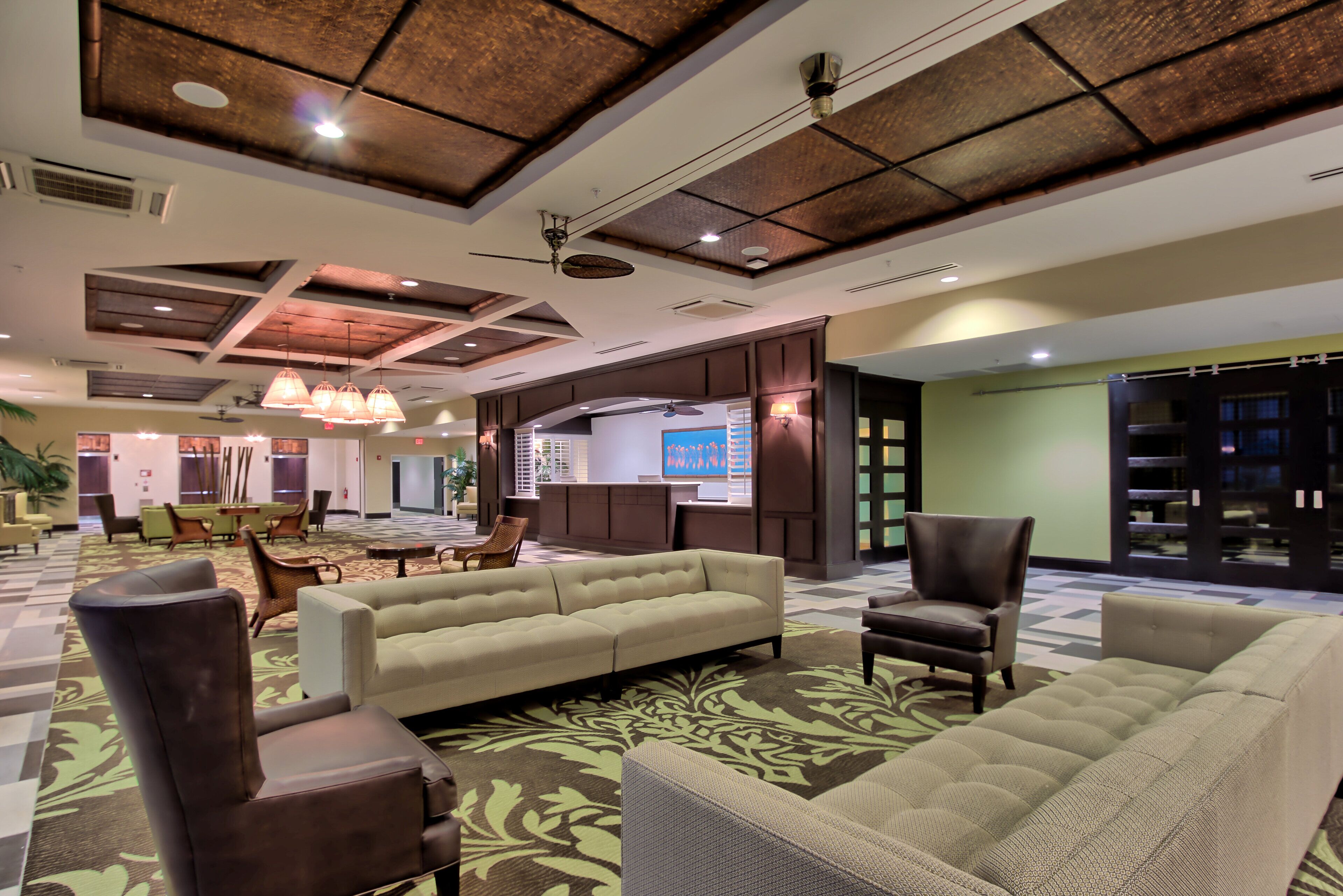 A spacious lobby with a high ceiling, modern furniture, and a large screen displaying information.