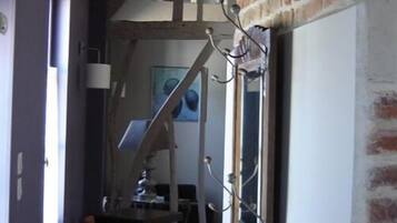 Un couloir étroit avec un cadre de porte en bois, un mur en briques et un tableau accroché au mur.
