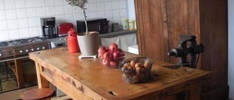 A kitchen with a wooden table, red cabinets, a gas stove, and a coffee maker.