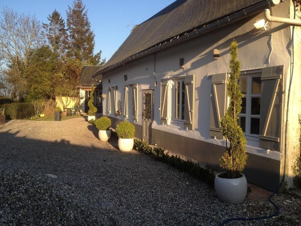 A building with a gravel driveway, potted plants, and a clear sky.