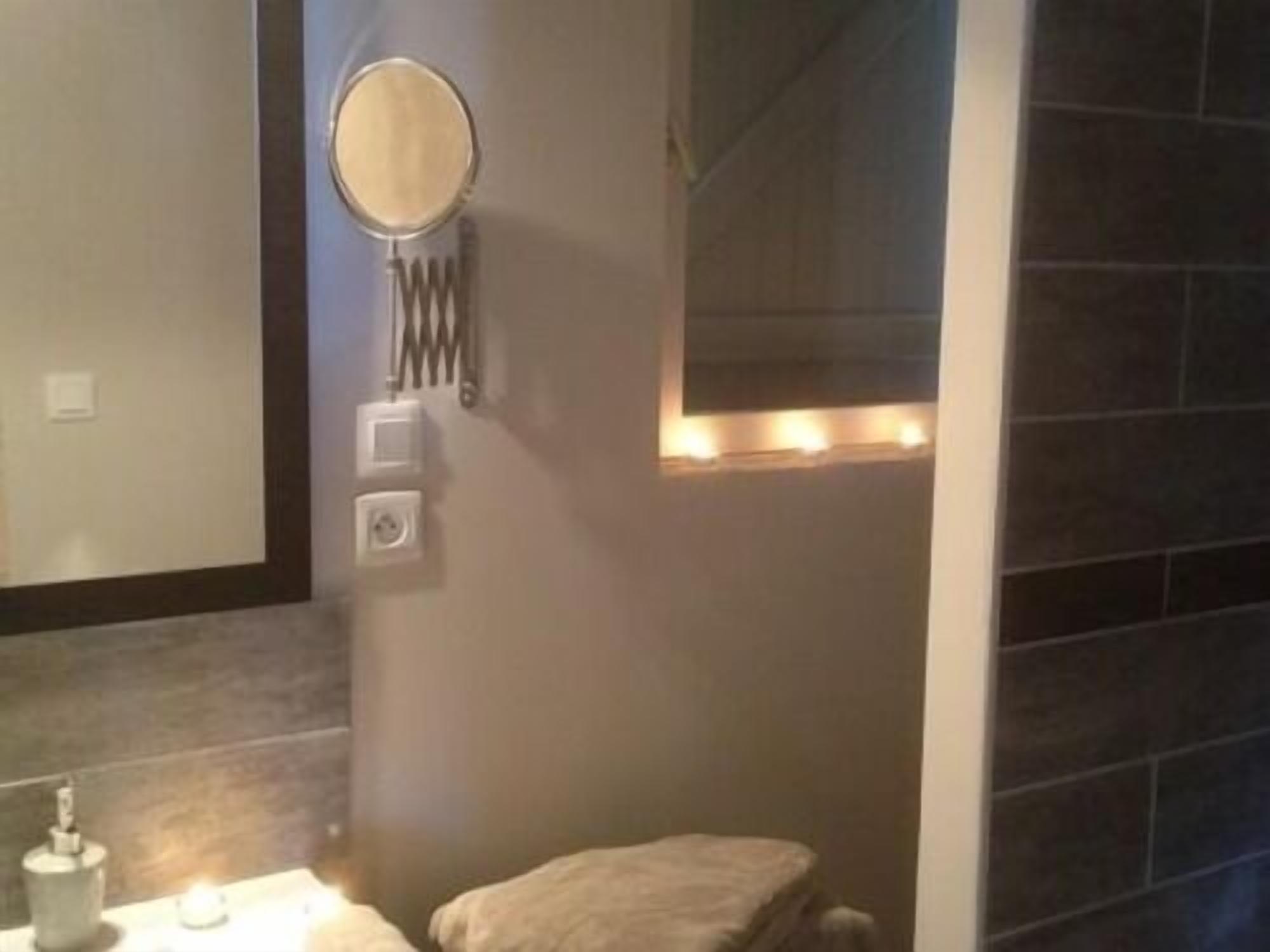 Un baño con inodoro, espejo y una lámpara de pared.