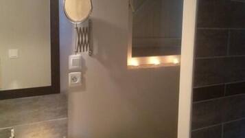 Un baño con inodoro, espejo y una lámpara de pared.