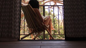 A person sitting on a chair by a window with patterned curtains. - Hotel Alma Azul (El Cuco)