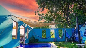 A pool area with a hammock, a tent, and a mural on the wall. - Hotel Alma Azul (El Cuco)