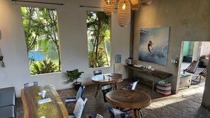A cozy, well-lit room with a large wooden table, several chairs, a water dispenser, and a painting on the wall. - Hotel Alma Azul (El Cuco)