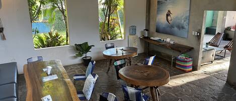 A cozy, well-lit room with a large wooden table, several chairs, a water dispenser, and a painting on the wall.