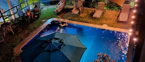 Ein Freibad mit Liegestühlen und Sonnenschirmen, umgeben von einer tropischen Wandmalerei.