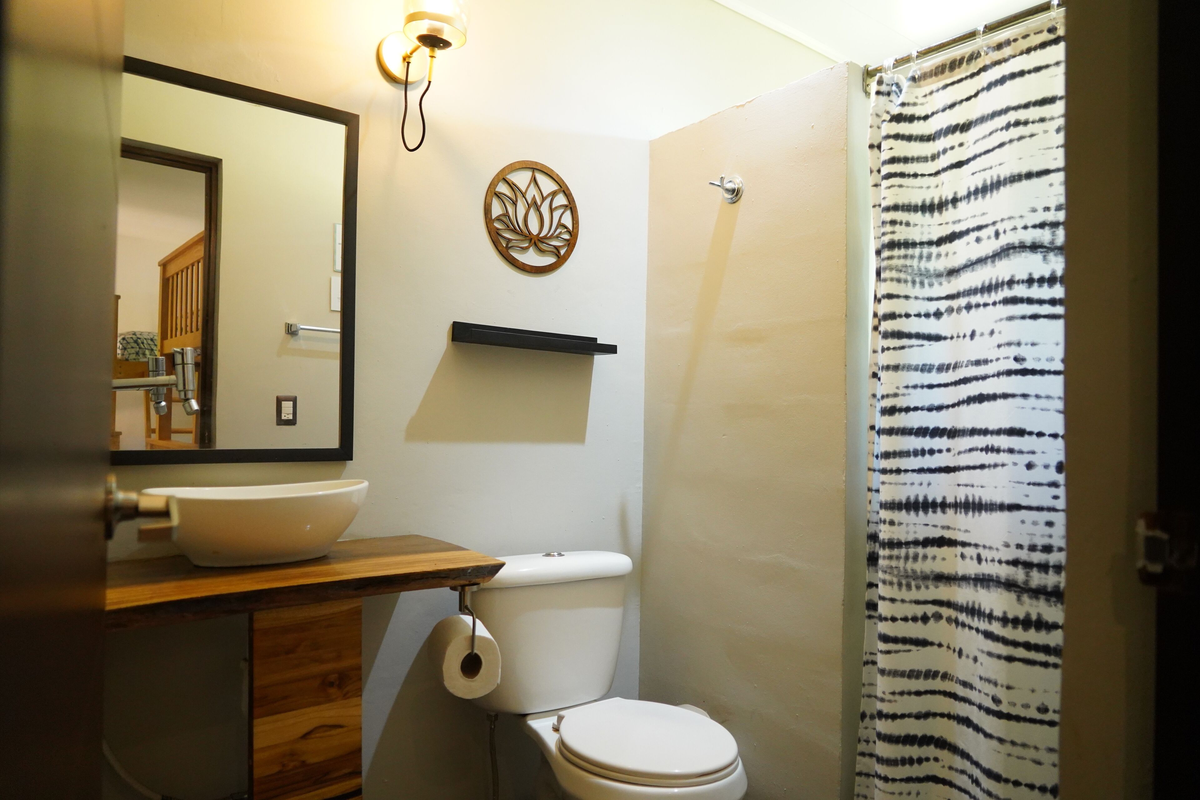 Une salle de bain avec un meuble-lavabo en bois, un lavabo blanc, des toilettes et un rideau de douche.