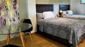 A hotel room with two beds, a glass table, and a modern abstract painting. - Hotel Alma Azul (El Cuco)