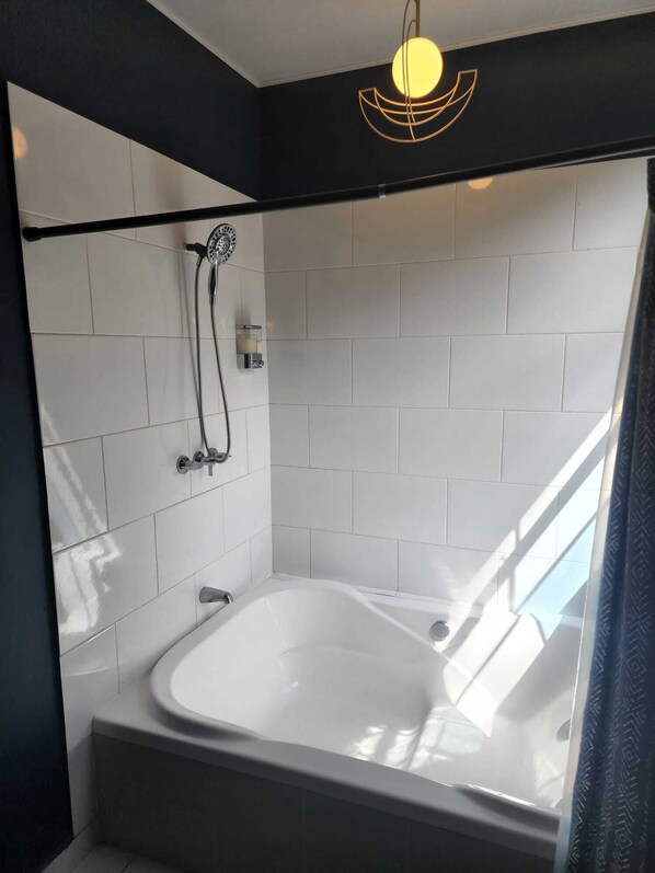 A modern bathroom with a freestanding bathtub, a showerhead, and a wall-mounted light fixture. - Hotel Alma Azul (El Cuco)