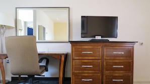 A room with a wooden desk, a chair, a television, and a dresser. - Laguna Lodge (Marina)