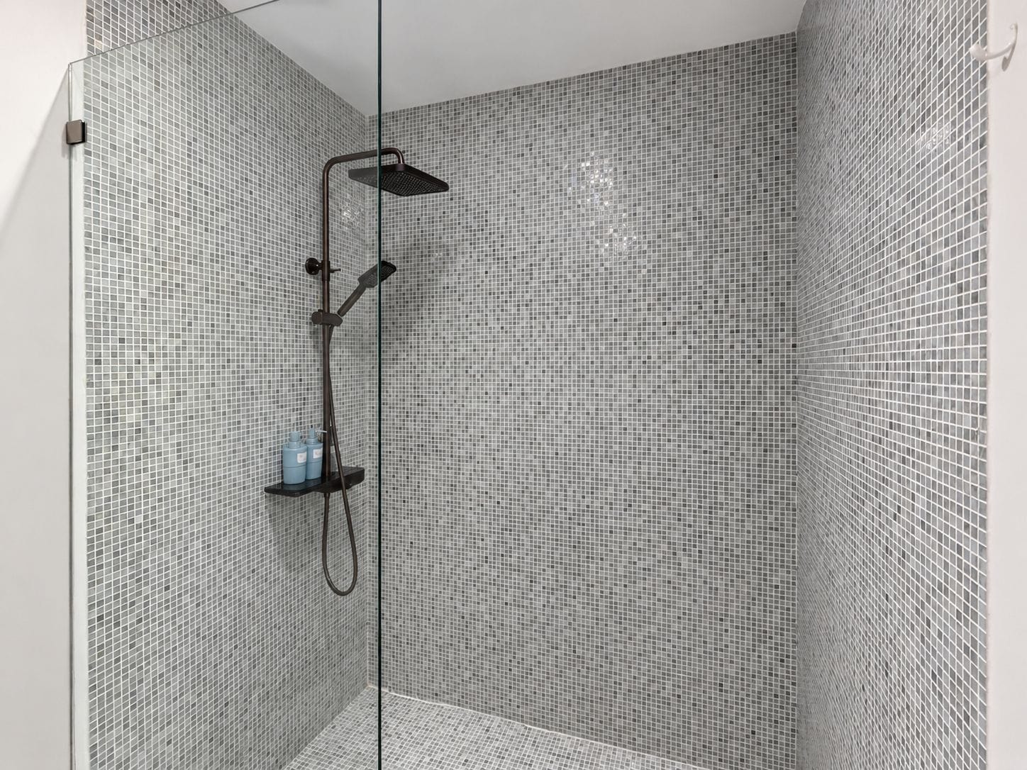 A shower with a glass door, tiled walls, and a showerhead.