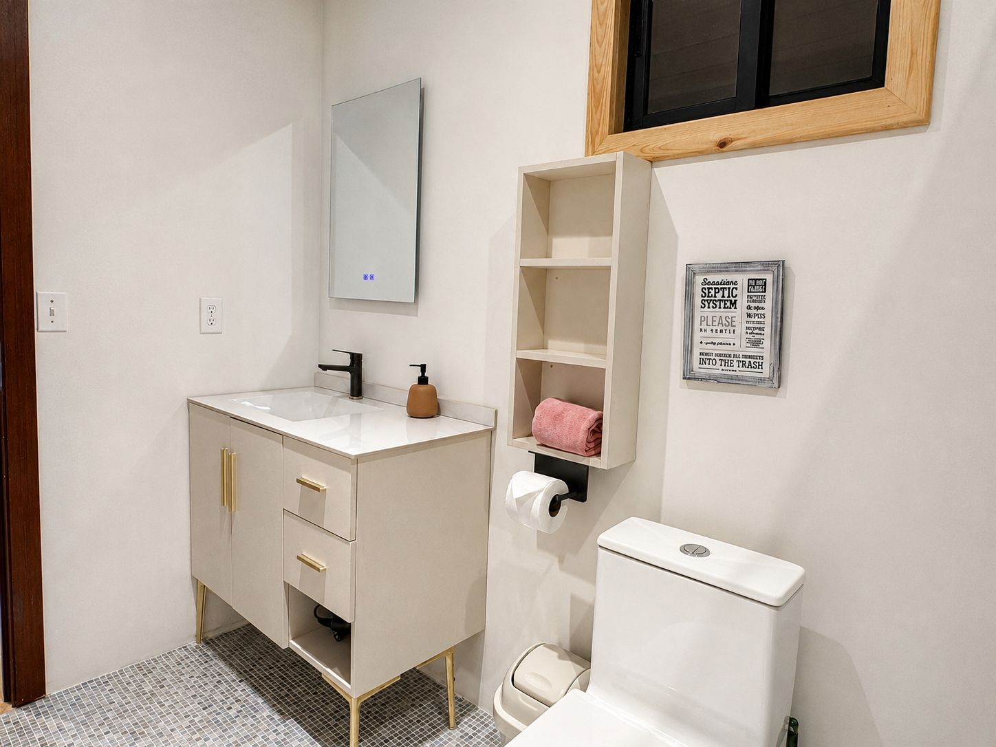 A bathroom with a white sink, a mirror, a toilet, and a shelf with a towel.
